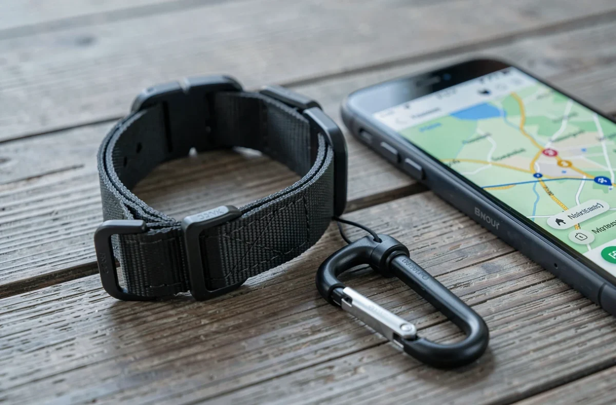 Collier GPS pour chien posé sur une table en bois avec application de suivi sur smartphone